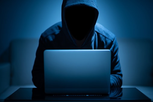 hacker dark face using laptop in the dark room