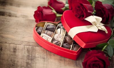 valentine's day box of chocolates and red roses on a wood background